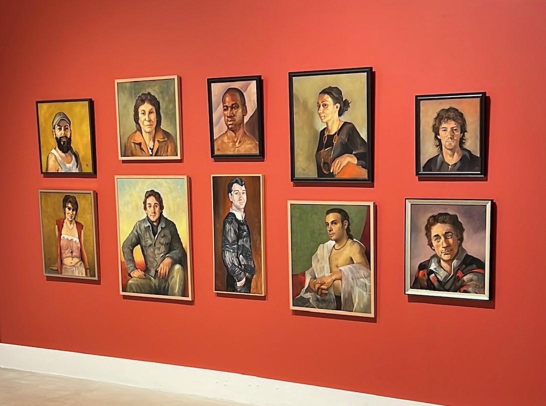 red wall with numerous portraits hung in two rows